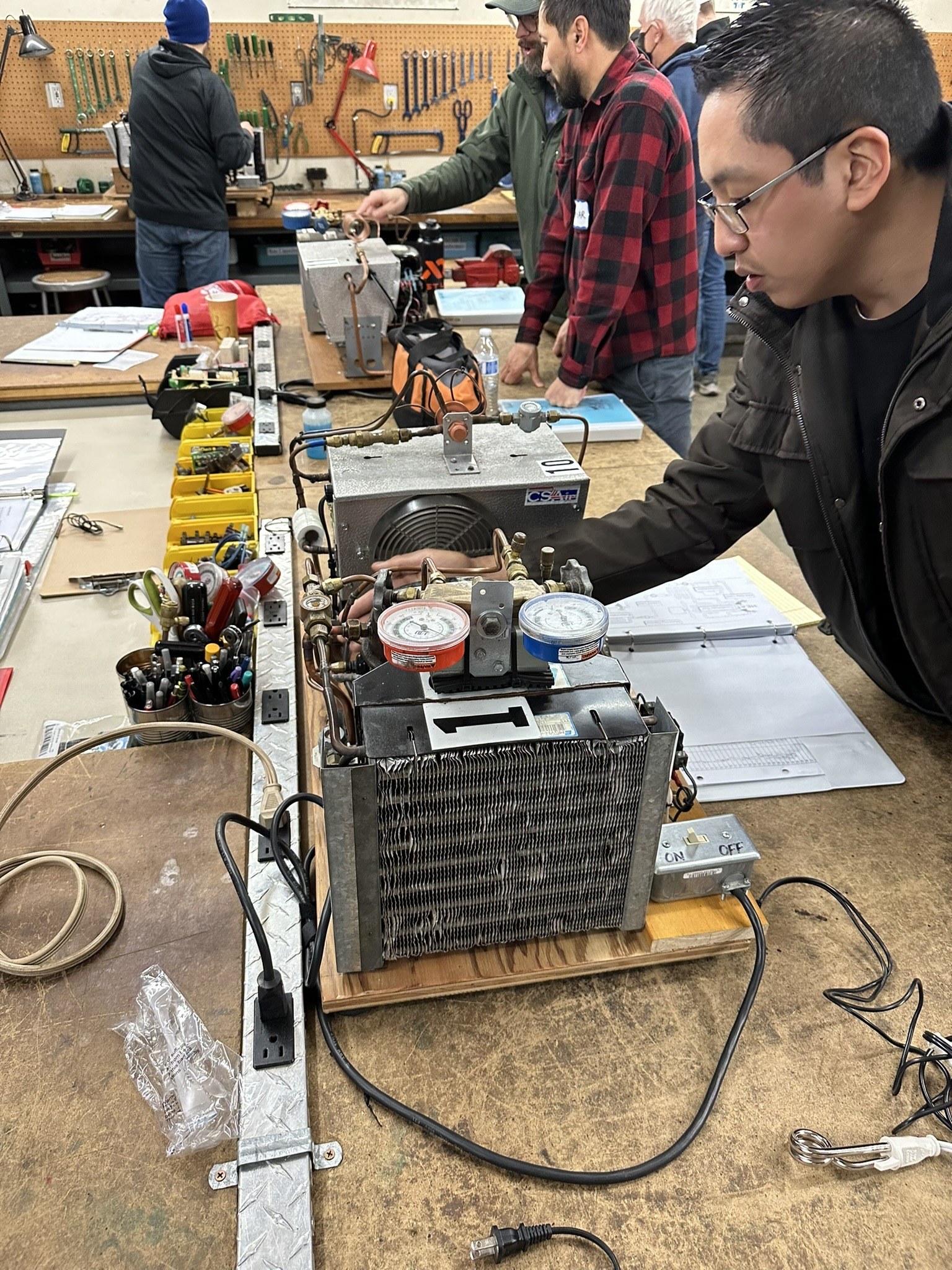 Focused troubleshooting at a training bench with authentic HVAC equipment