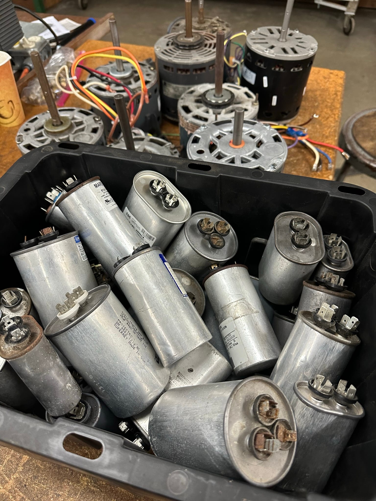 Bin of HVAC capacitors and fan motors staged for electrical testing practice